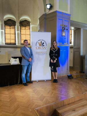 Laura Grabowski z nauczycielem biologii Szymonem Krawczykiem przy banerze Uniwersytetu Kazimierza Wielkiego w Bydgoszczy