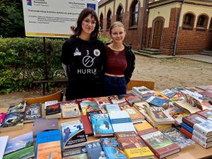 Kiermasz książek na festynie "Wspólnie dla czworonogów". Za stołem z książkami stoją dwie uczennice.