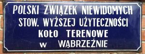 Tabliczka z napisem "POLSKI ZWIĄZEK NIEWIDOMYCH STOW. WYŻSZEJ UŻYTECZNOŚCI KOŁO TERENOWE W WĄBRZEŹNIE".