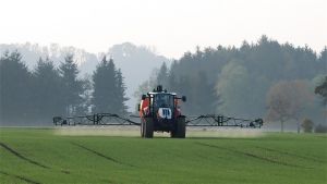 Traktor z opryskiwaczem na polu.