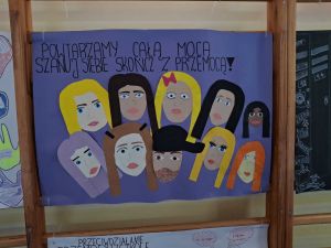 Plakat z napisem "POWTARZAMY CAŁĄ MOCĄ SZANUJ SIEBIE SKOŃCZ Z PRZEMOCĄ"