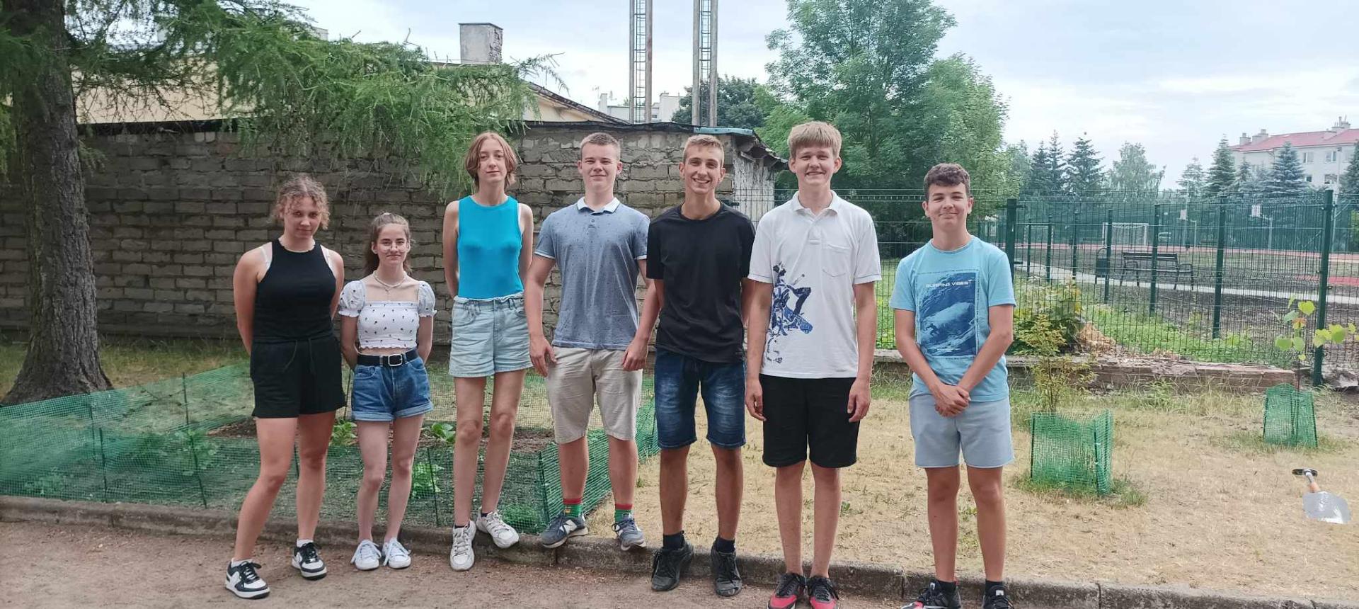 Uczniowie na tle przyszkolnego ogródka